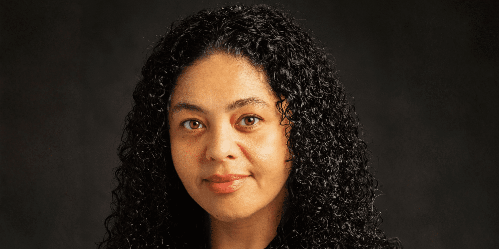 Headshot of Charlotte Sanders against a dark background.