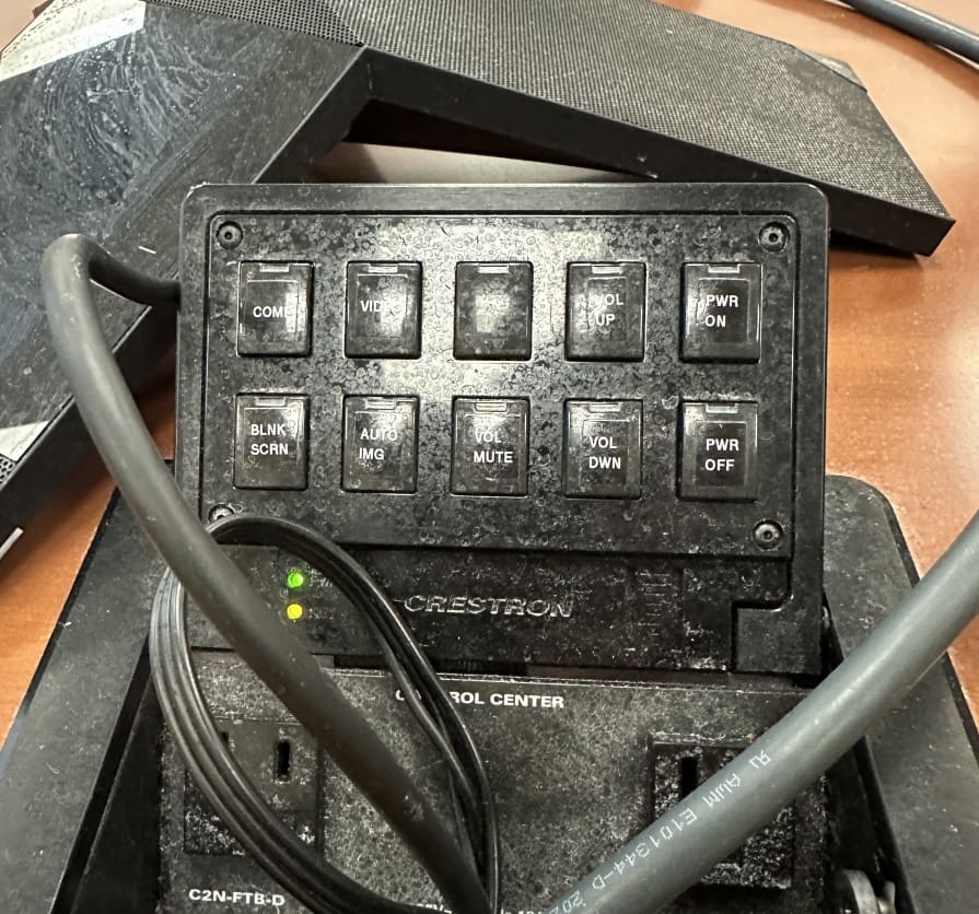 Black Creston box with buttons on the surface and multiple cables surrounding it.